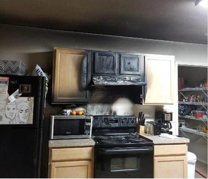 kitchen after fire cabinets and stove area covered in soot
